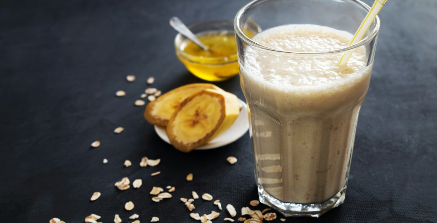 A glass of milk with a spoon next to it